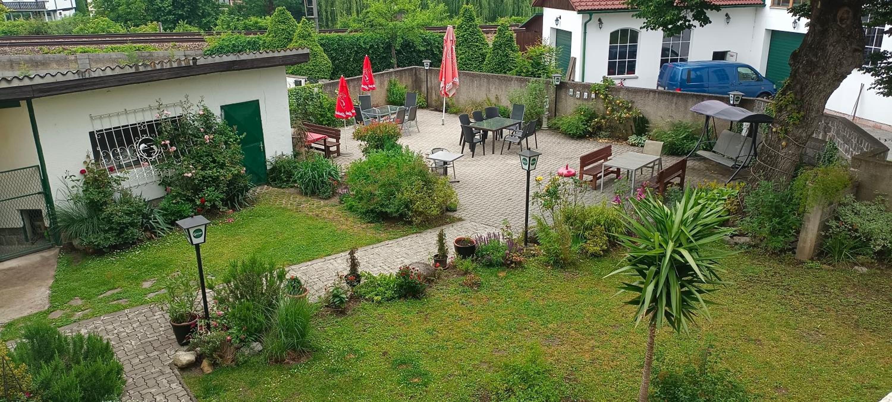 A courtyard with outdoor seating, a garden area, and a building with a green door.