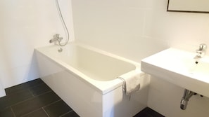 A bathroom with a bathtub, a sink, and a shower. - Gasthaus Schwarzer Adler (Sankt Andrae-Woerdern)