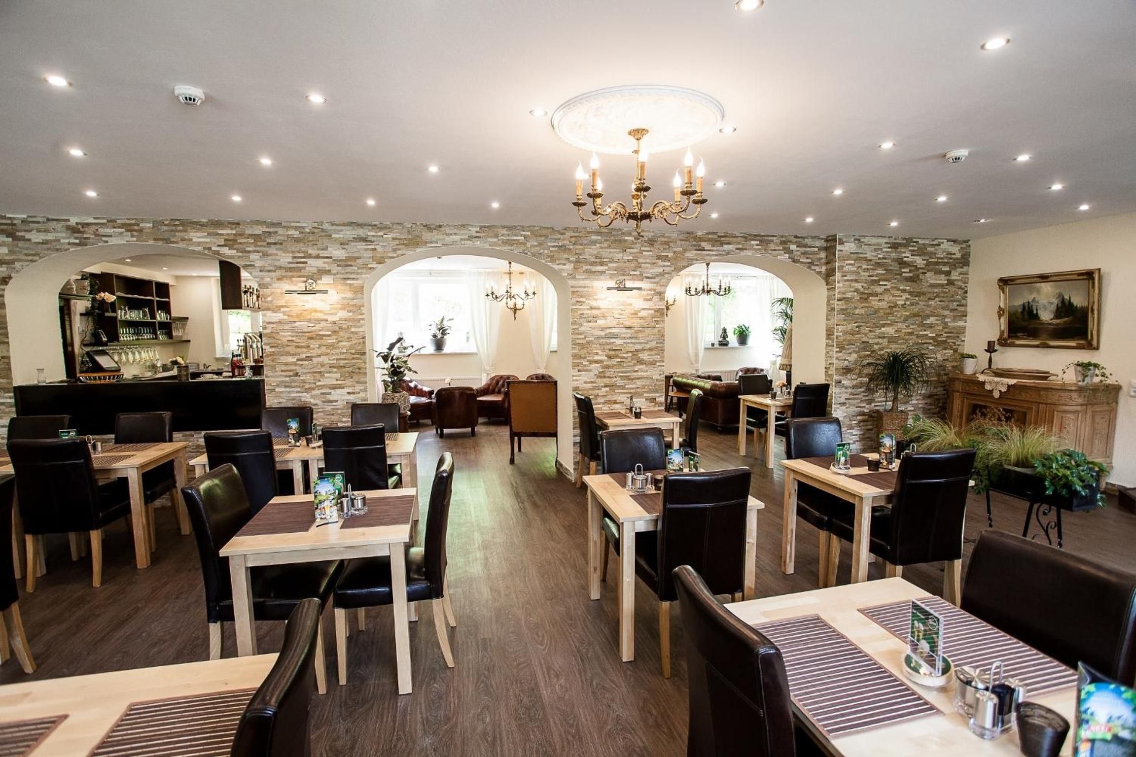 A restaurant with a stone wall interior, multiple dining tables, and chairs.