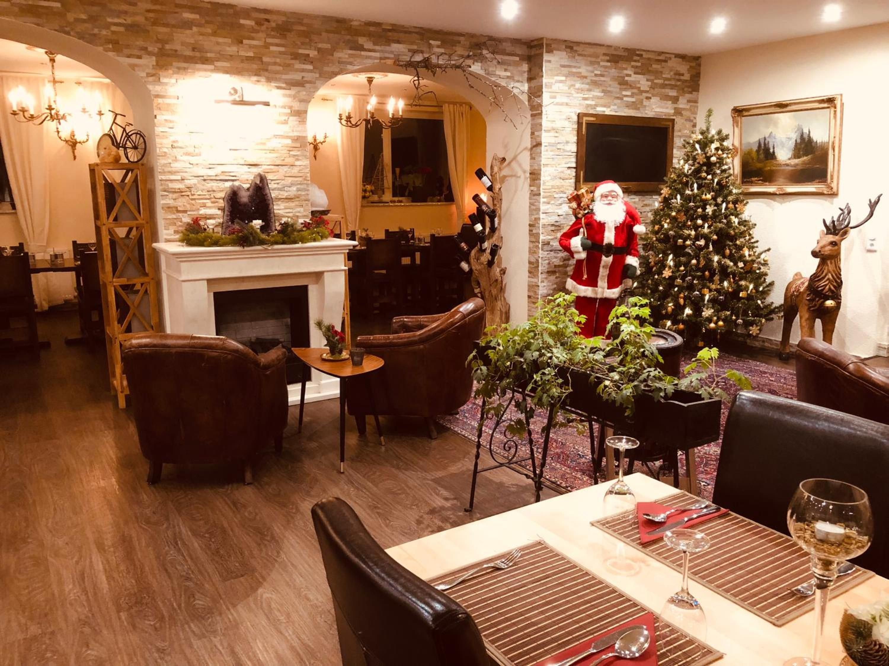 Zona pranzo con camino, poltrone in pelle, albero di Natale e decorazione con Babbo Natale.