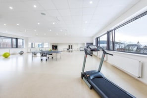Uma academia espaçosa com esteira, bolas de exercício e mesa de pingue-pongue.