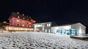 Hotel com vários edifícios, incluindo uma estrutura vermelha e outra branca, e terreno coberto de neve.
