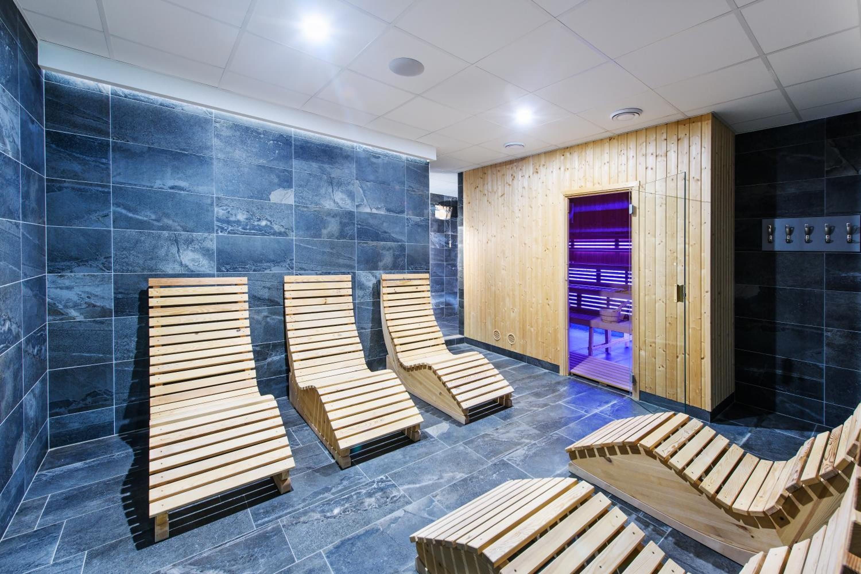 A sauna area with wooden loungers and a wooden wall.