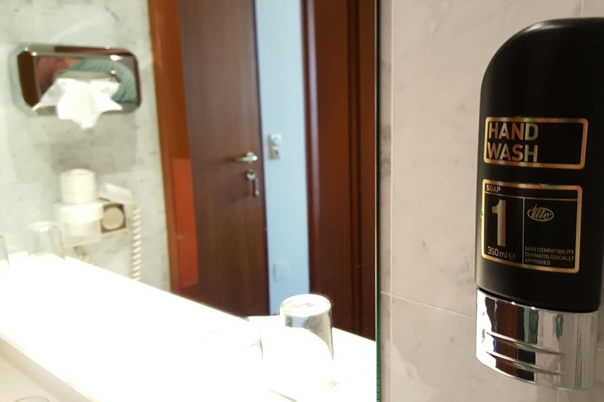 A hand wash station with a soap dispenser, a mirror, and a towel rack in a bathroom.
