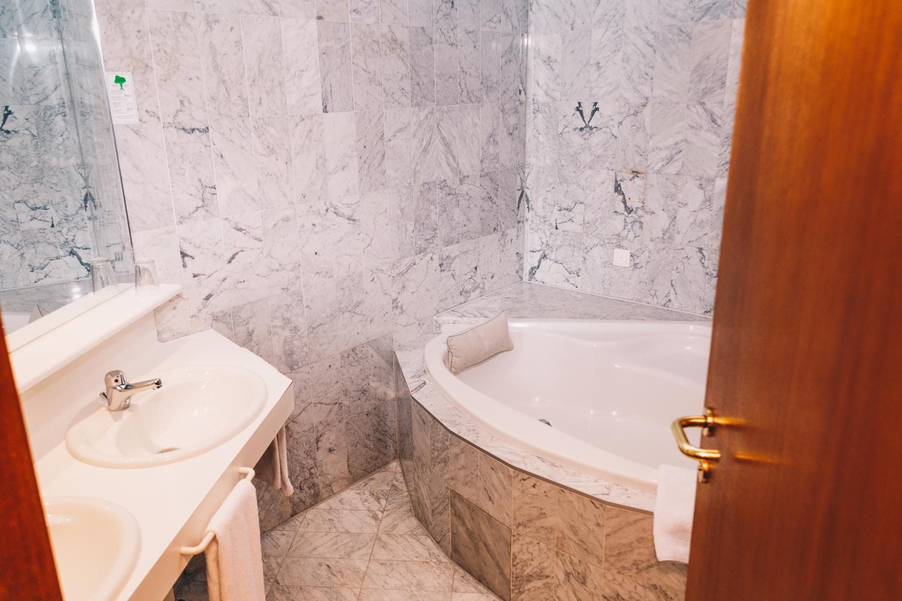 A bathroom with a marble wall, a sink, and a bathtub.