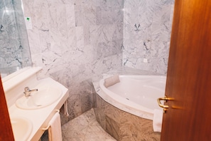Un baño con pared de mármol, un lavamanos y una bañera.