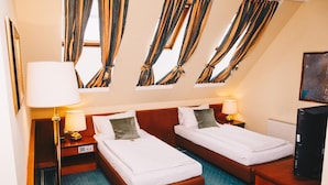 A hotel room with two beds, a desk, a chair, a television, and curtains. - Paul S Hotel (Knittelfeld)