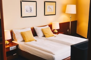 A double bed with white linens and two pillows, a bedside table with a lamp, and two framed artworks on the wall. - Paul S Hotel (Knittelfeld)