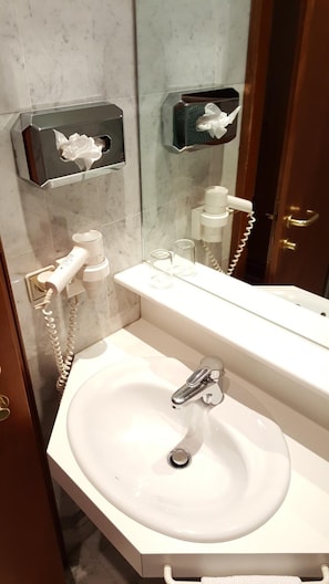 A bathroom with a white sink, a mirror, a towel dispenser, and a hairdryer. - Paul S Hotel (Knittelfeld)
