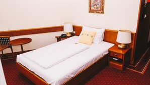 A hotel room with a single bed, a bedside table with a lamp, a chair, and a framed picture on the wall. - Paul S Hotel (Knittelfeld)