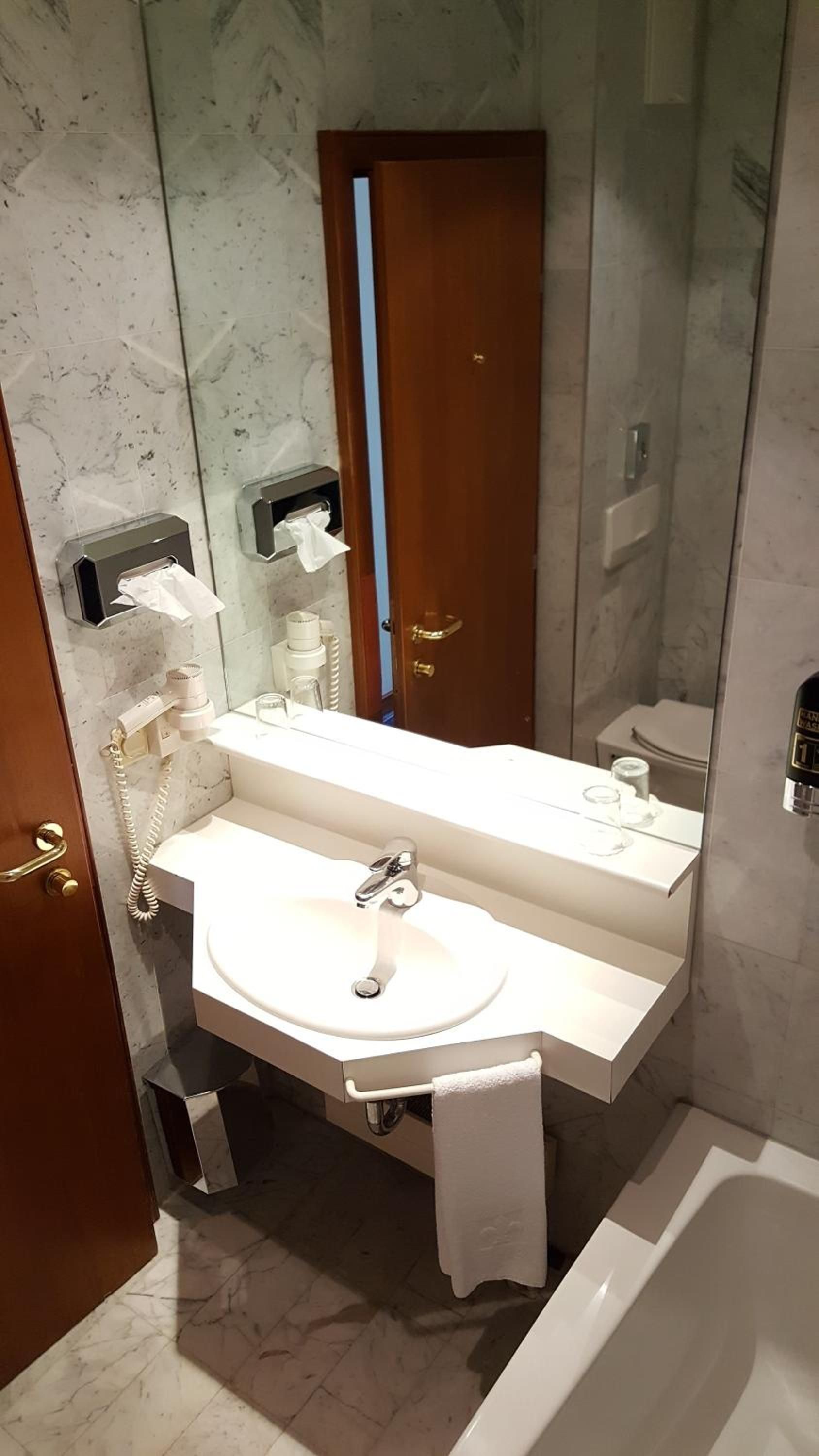 A bathroom with a white sink, a mirror, a towel rack, and a toilet.