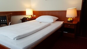 A hotel room with a single bed, two bedside lamps, a chair, and a nightstand with a telephone. - Paul S Hotel (Knittelfeld)