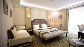 A hotel room with a double bed, a single bed, a desk, and a chair.