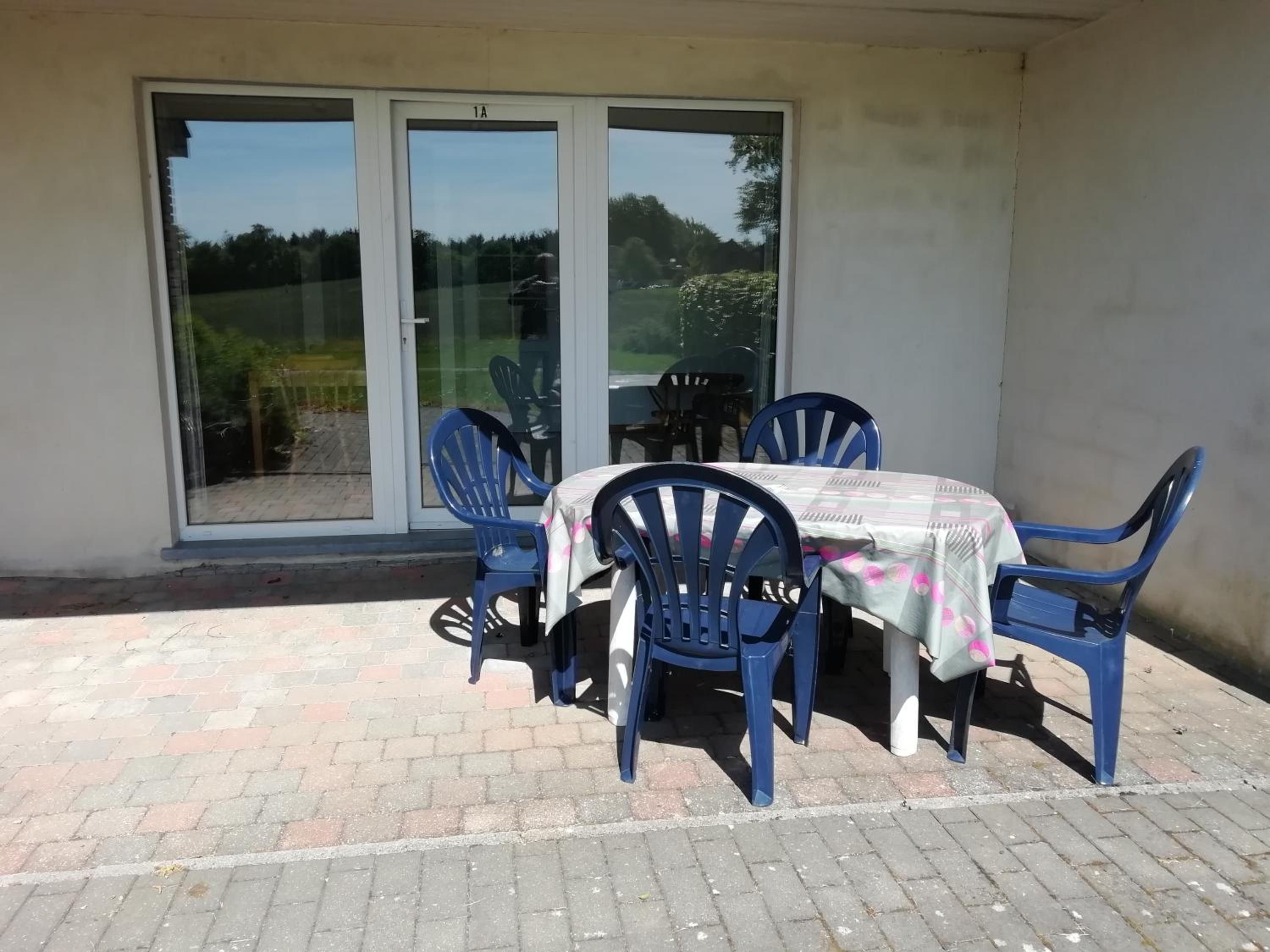 Una zona con patio, un tavolo, sedie, una porta scorrevole in vetro e un pavimento in mattoni.