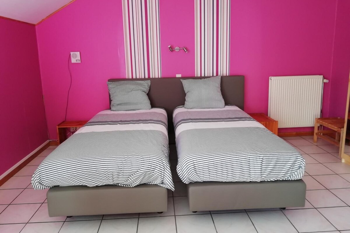 A room with two beds, a radiator, and a small wooden table.