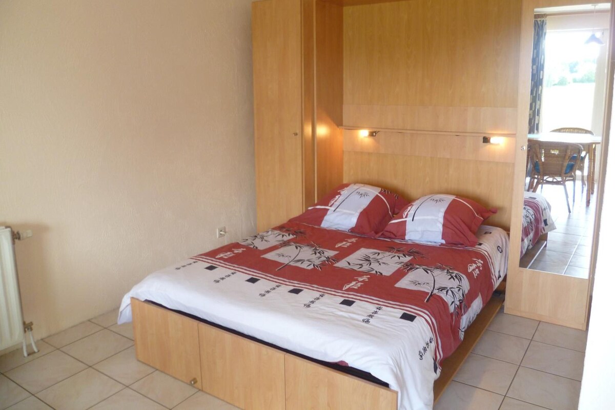 Un dormitorio con cama, armario de madera y espejo.