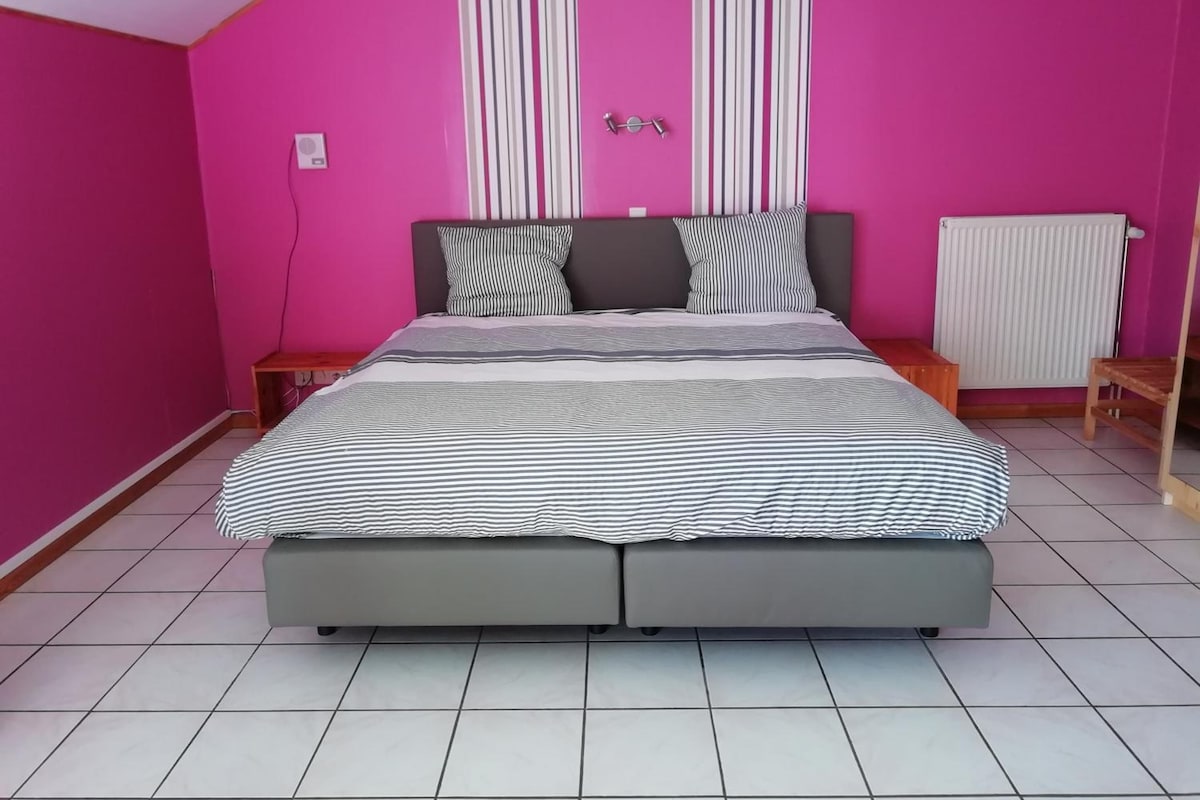 Un dormitorio con una cama, un radiador y una ventana.