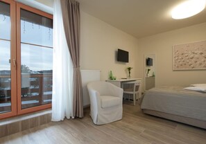 Una habitación de hotel con una cama, un escritorio, una silla, un televisor y una ventana con cortinas.