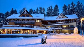 A hotel with multiple floors, outdoor seating, and snow-covered surroundings. - Hotel Slune Anva Louka (Lipno nad Vltavou)