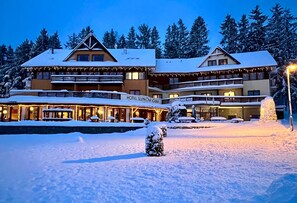 Un hotel de varios pisos, con mesas al aire libre y un entorno cubierto de nieve.