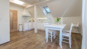 A modern kitchen with white cabinetry, a dining table with chairs, and a skylight. - Hotel Slune Anva Louka (Lipno nad Vltavou)
