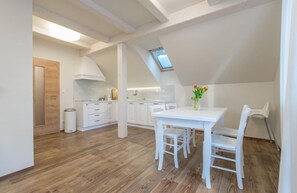 Una cocina moderna con armarios blancos, una mesa de comedor con sillas y un tragaluz.