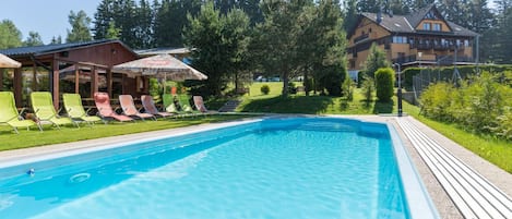 A swimming pool with lounge chairs and a wooden deck.