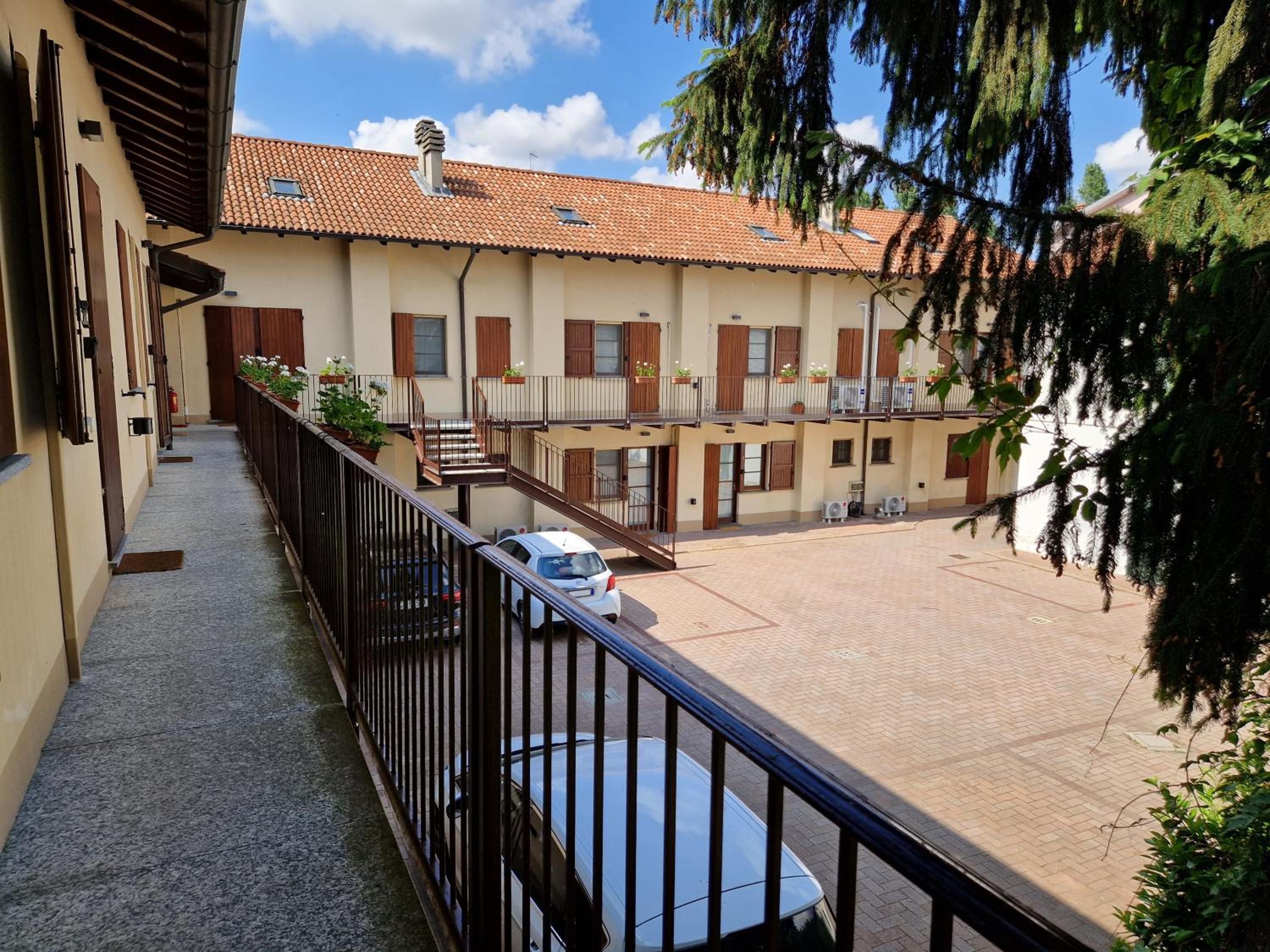 A multi-story building with a courtyard, balconies, and a car parked in front.