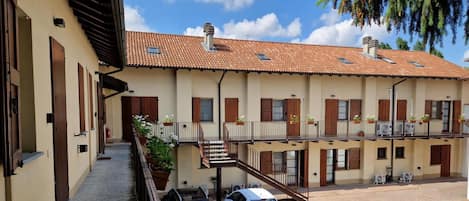 Un bâtiment à deux étages, doté d’un toit en tuiles, de balcons avec des garde-corps et d’une cour pavée.