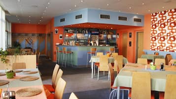 Um restaurante com área de bar, várias mesas e cadeiras.
