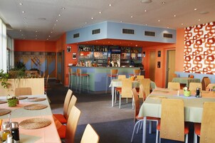 Un restaurante con barra, varias mesas y sillas.