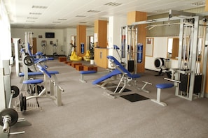 Un gimnasio con varios equipos de ejercicio, incluyendo máquinas de pesas y pesas libres.