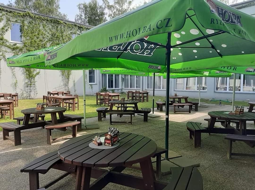 An outdoor seating area with green umbrellas and wooden tables.