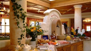 A breakfast buffet with a variety of food items, a decorative archway, and a rustic interior design. - Landhaus Appartementhaus Haussteiner (Dorfgastein)