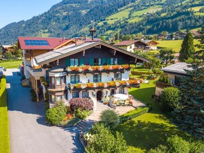 A two-story chalet with a sloped roof, a balcony with flower boxes, and a well-maintained garden. - Landhaus Appartementhaus Haussteiner (Dorfgastein)