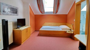 A bedroom with a bed, a television, a radiator, and a window with curtains. - Gasthof Huber (Wels)