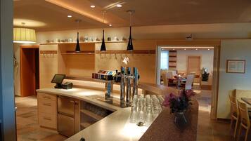 Eine Hotelbar mit Theke, Barhocker und einer Auswahl an Flaschen.