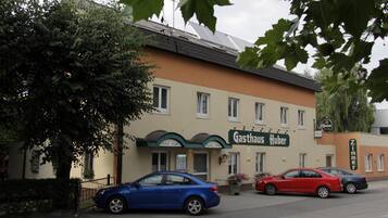 Ein Gebäude mit einem Schild, auf dem 'Gasthaus Huber' steht, und zwei Autos davor geparkt.