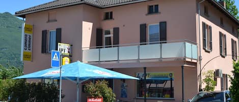 A building with a balcony, outdoor seating, and a sign for a restaurant.