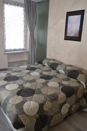 Un dormitorio con una cama, una ventana con cortinas y un cuadro en la pared.