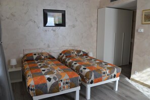 Un dormitorio con dos camas, una mesita de noche, un cuadro enmarcado en la pared y un armario.