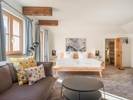 A bedroom with a bed, a sofa, a coffee table, and a painting on the wall.