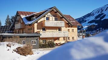Eine zweistöckige Chalet mit Holzfassade, einem Balkon und einem Blick auf die Berge.