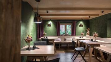 Ein gemütliches Restaurant mit Holztischen und -bänken, grünen Wänden und Pendelleuchten.