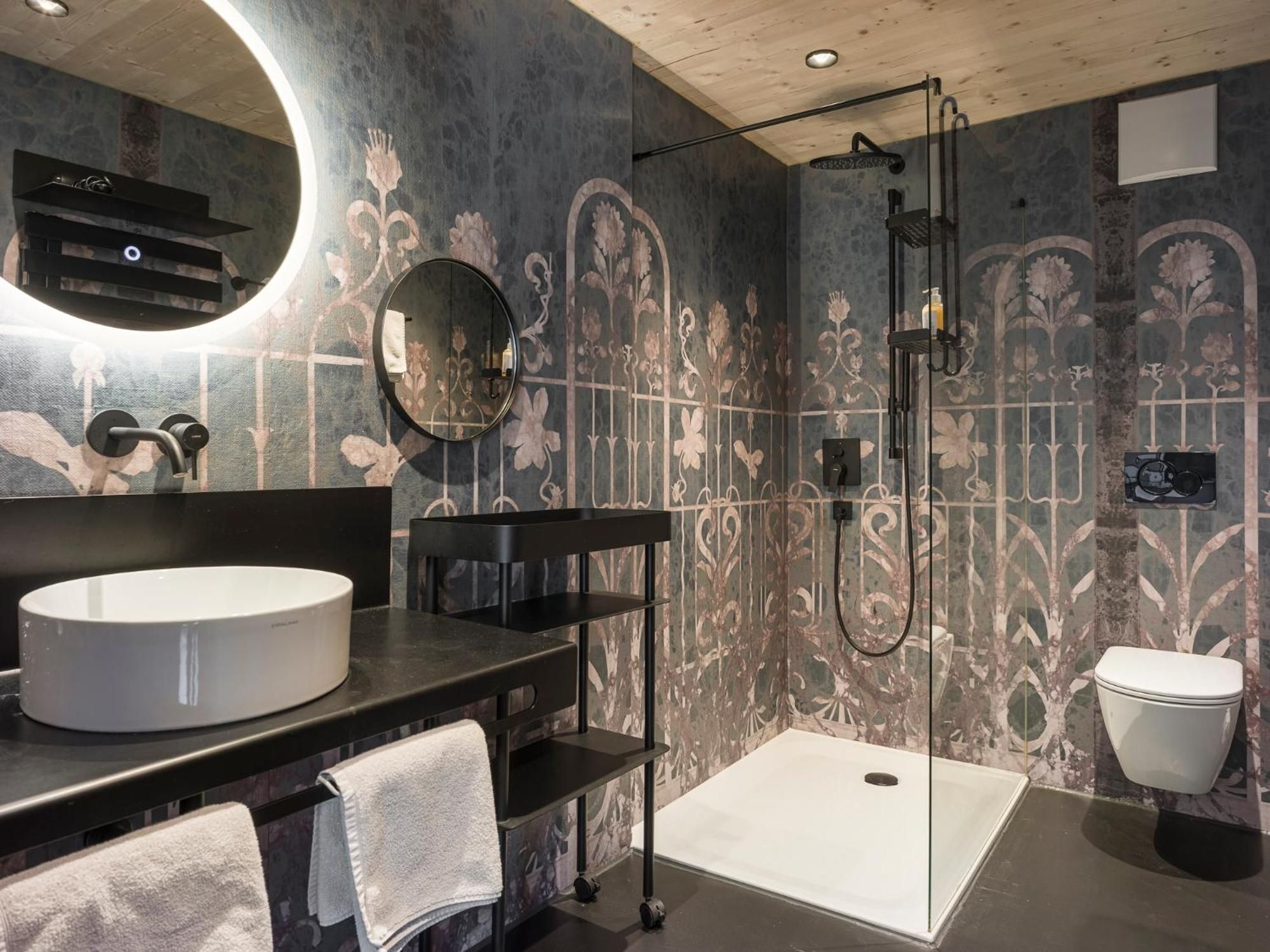 Ein modernes Badezimmer mit rundem Spiegel, Waschbecken, Toilette und Duschbereich.