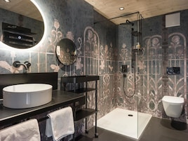 A modern bathroom with a round mirror, a sink, a toilet, and a shower area.