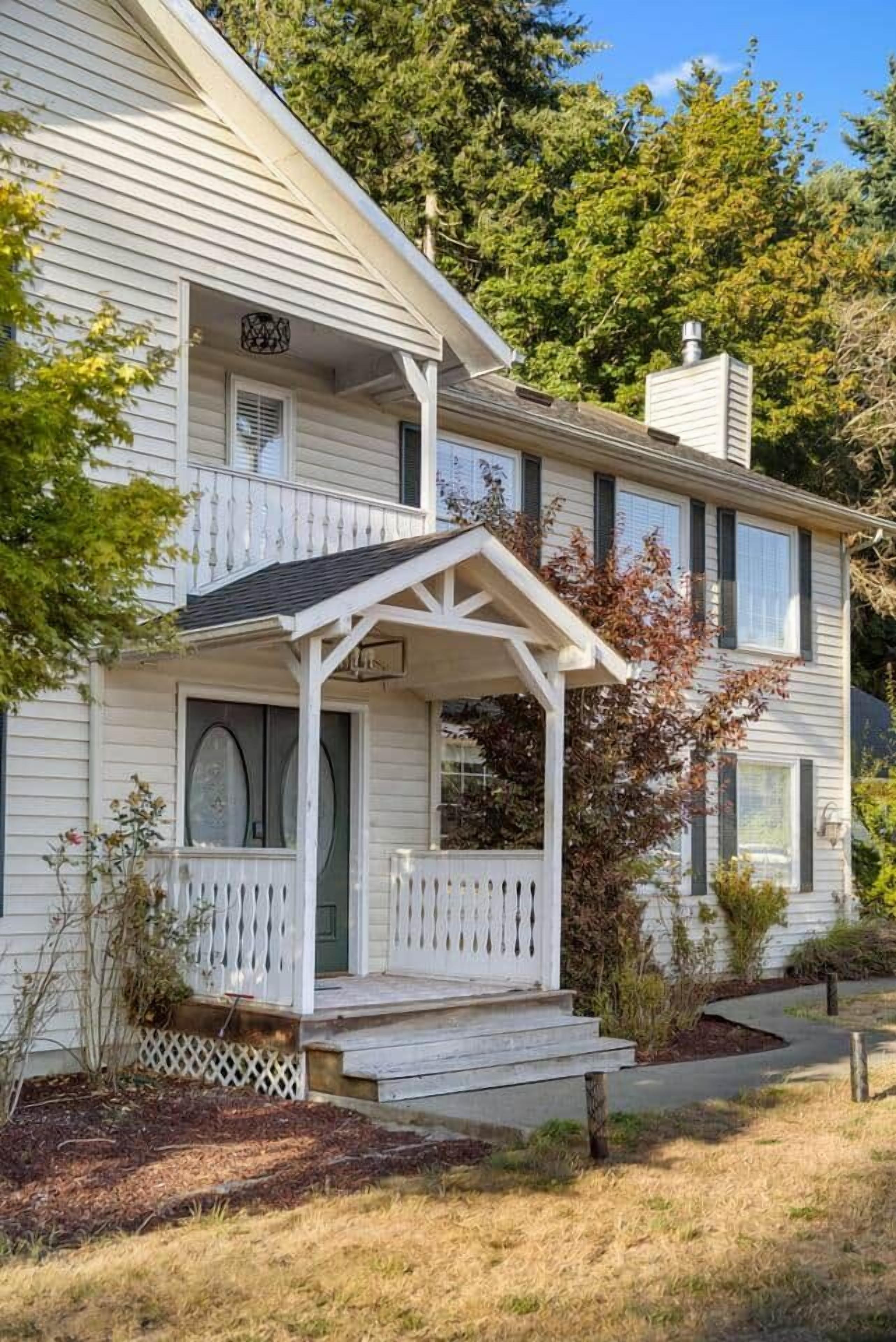 Een huis met twee verdiepingen, een veranda en een kleine tuin.