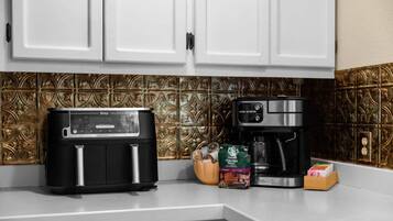 A kitchen with a black toaster, a coffee maker, and a bag of coffee beans.