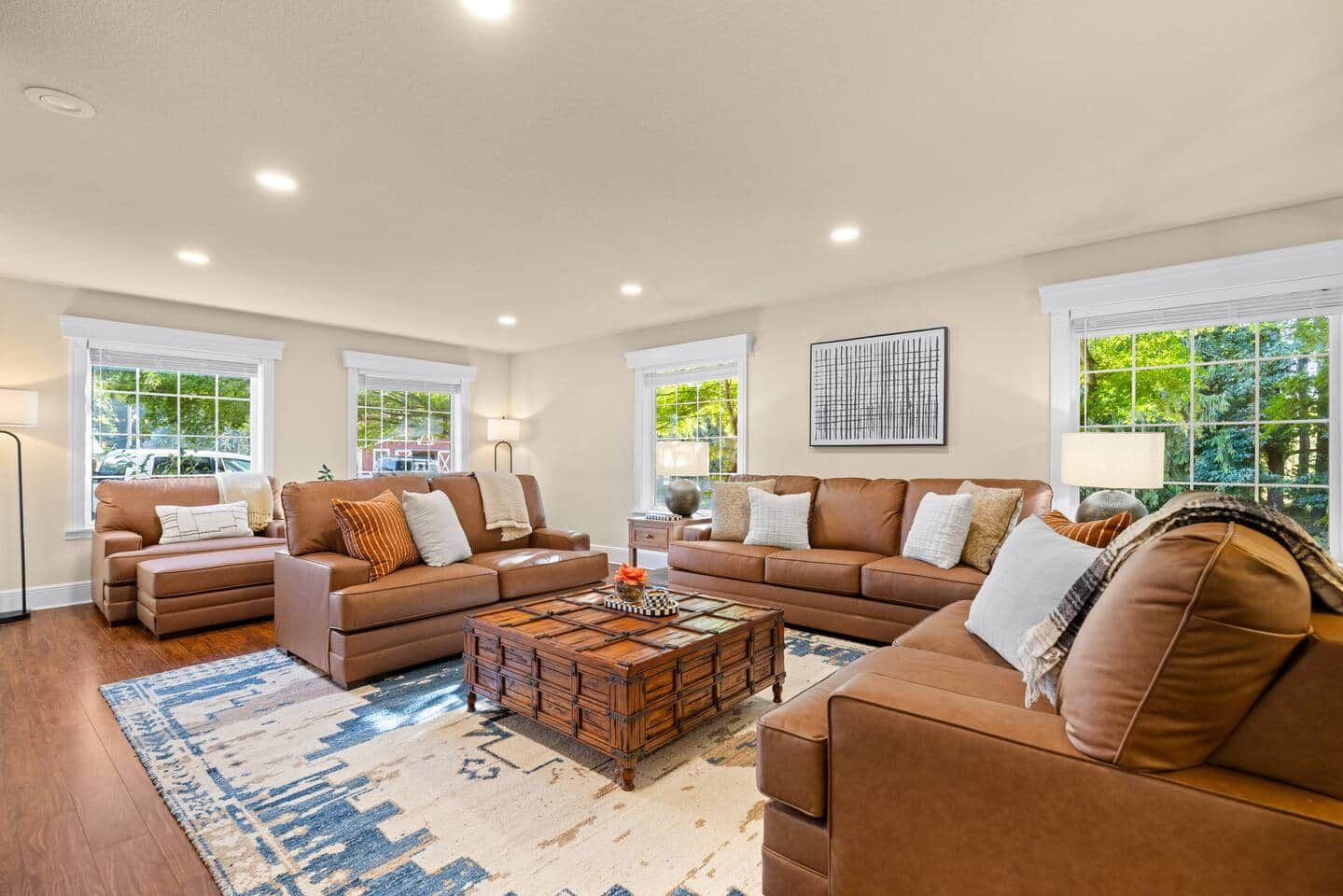 A spacious living room with a large sectional sofa, a coffee table, and a view of the outdoors through large windows.
