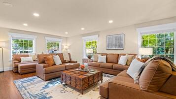 A spacious living room with a large sectional sofa, a coffee table, and a view of the outdoors through large windows.